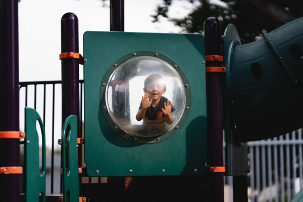 Child looks out bubble window on playground